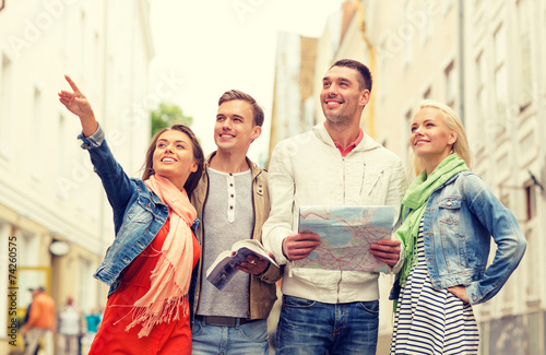 group of smiling friends with city guide and map