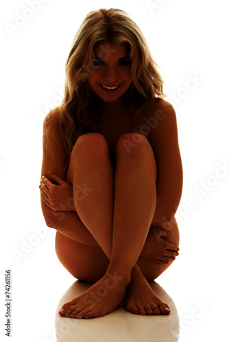Nude woman sitting with knees close to the chest
