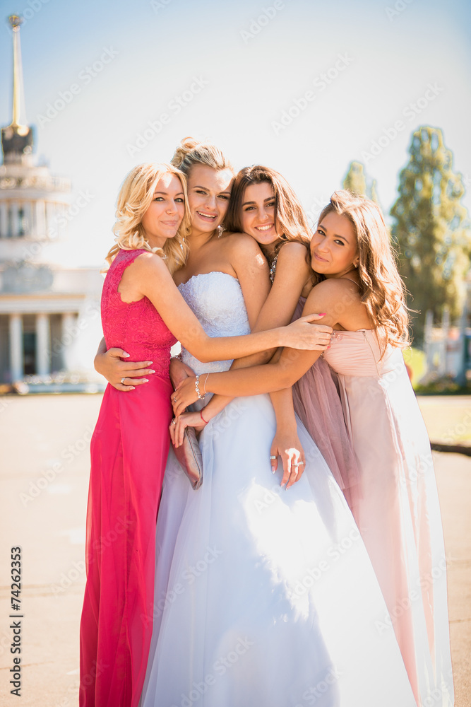 beautiful bride hugging with bridesmaids at sunny day