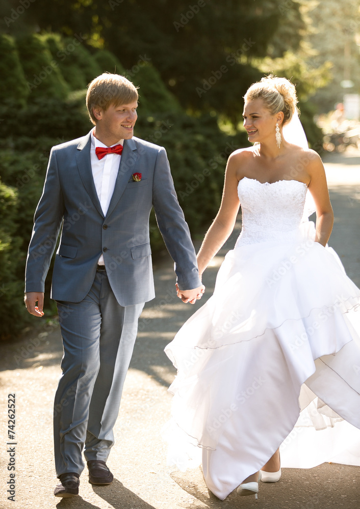 bride and groom holding hands while walking at park bride and groom holding hands while walking at park