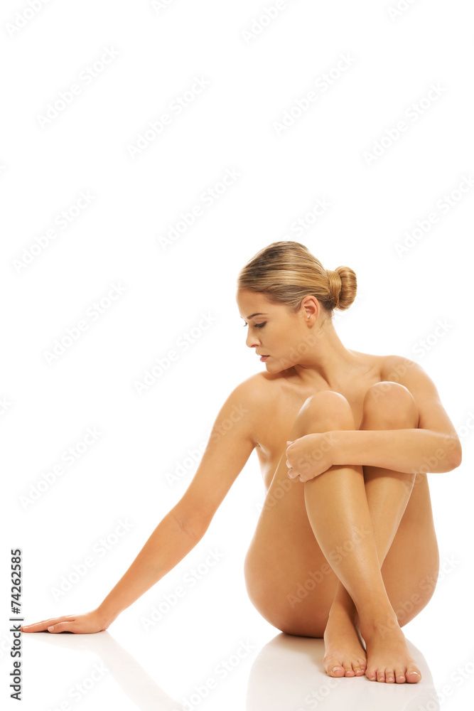 Fototapeta premium Nude woman sitting on the floor buttres her hands