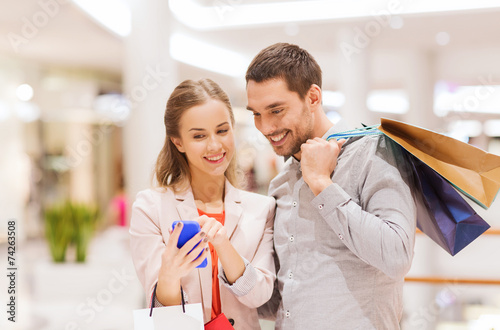 couple with smartphone and shopping bags in mall photo