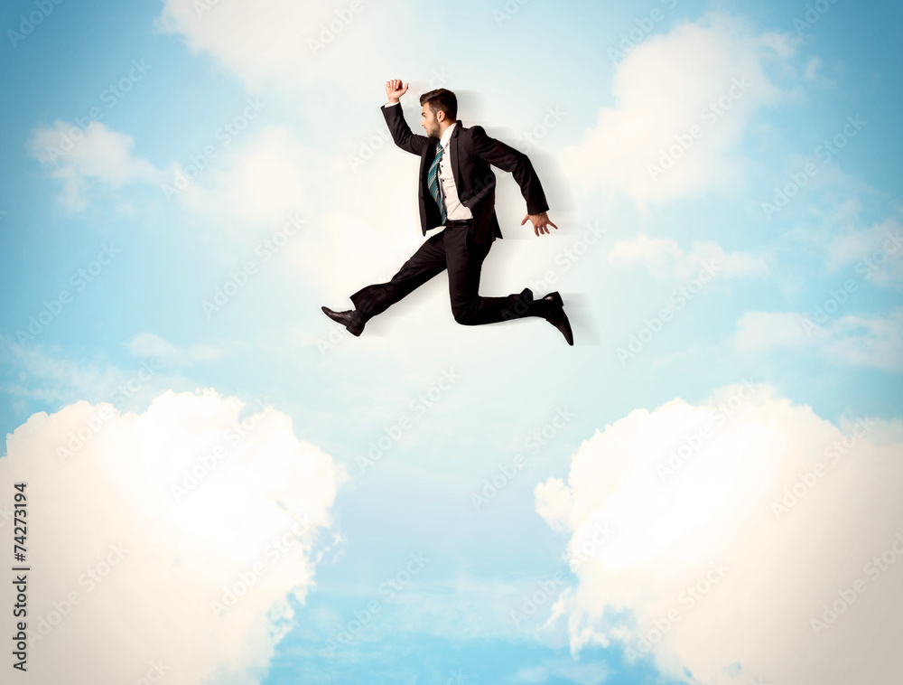 Business person jumping over clouds in the sky Business person jumping over clouds in the sky