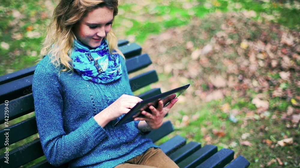 Girl using tablet in the park and sitting on the bench Girl using tablet in the park and sitting on the bench