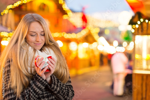 Junge Frau trinkt Glühwein auf dem Weihanchtsmarkt