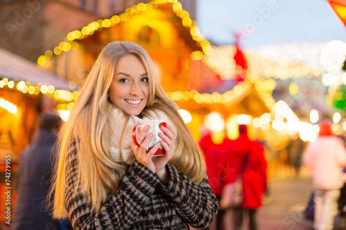 Junge Frau trinkt Glühwein auf dem Weihanchtsmarkt photo