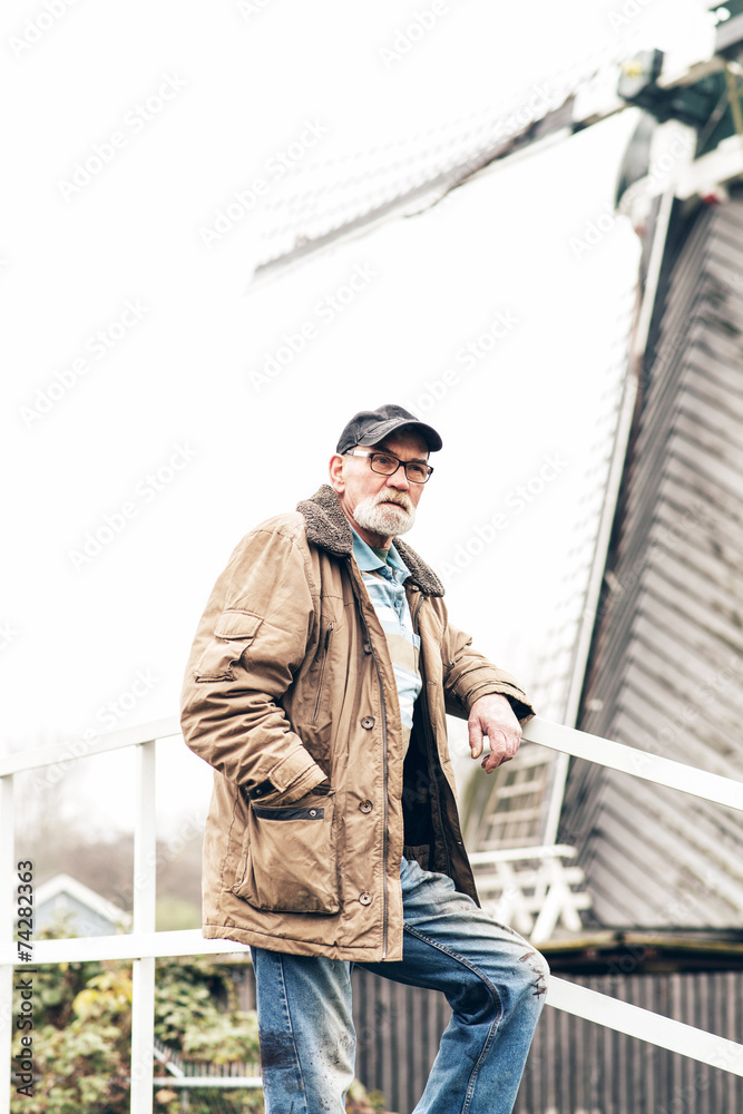 Senior man with beard wearing glasses and black cap outdoor in w