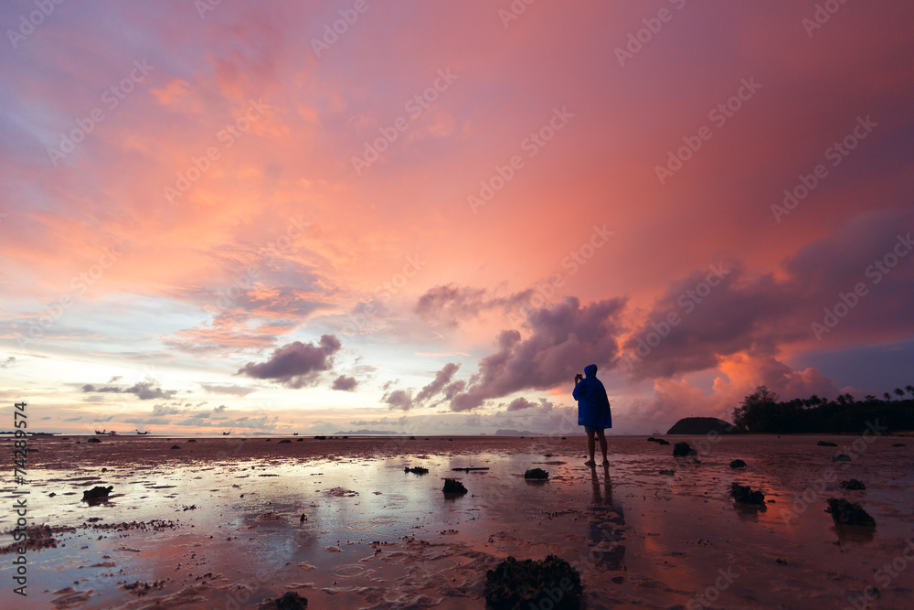 girl making photo pink sunset over the sea