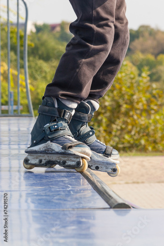 Teen with roller skates performing a stunt on a half pipe ramp.
