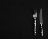 Fine cutlery on black placemat as menu board