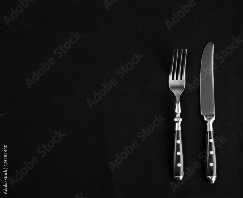 Fine cutlery on black placemat as menu board