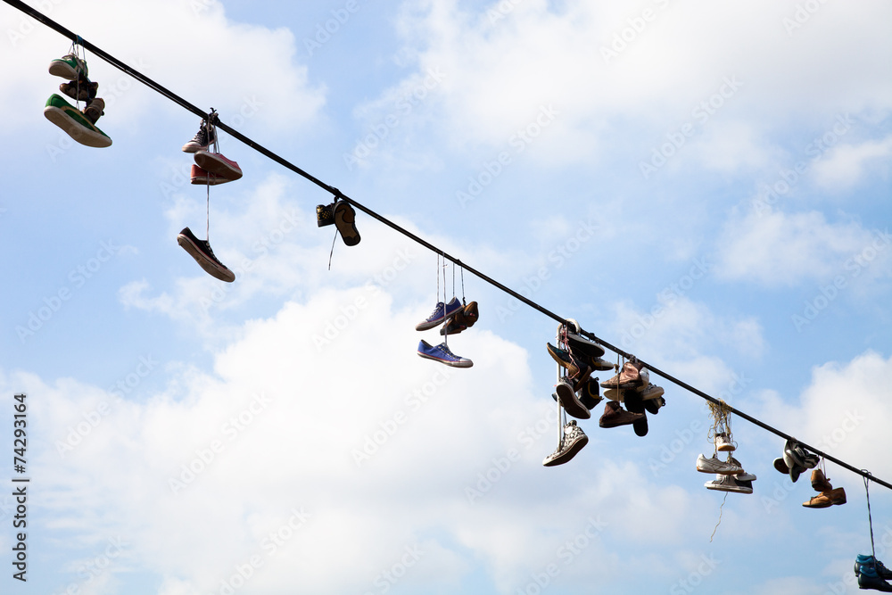 Old Shoes hanging on electrical wire against a blue sky Old Shoes hanging on electrical wire against a blue sky