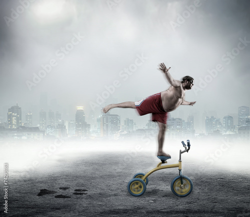 Nerdy man standing on a small bicycle