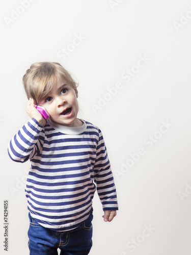 Cute little girl talking with a pink phone isolated