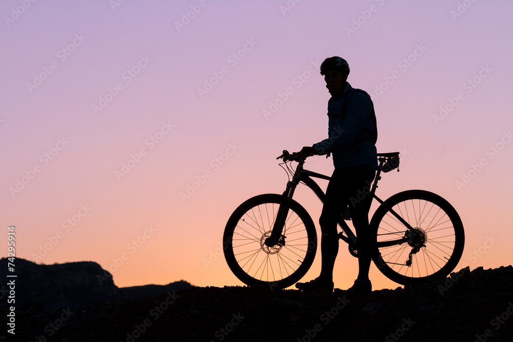 Silhouette of a cyclist with sunset on the top of a hill Silhouette of a cyclist with sunset on the top of a hill