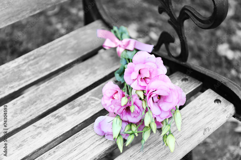 Fototapeta premium Beautiful bouquet of eustoma flowers on wooden bench in park