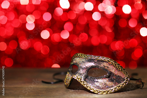 Beautiful carnival mask on table on red background