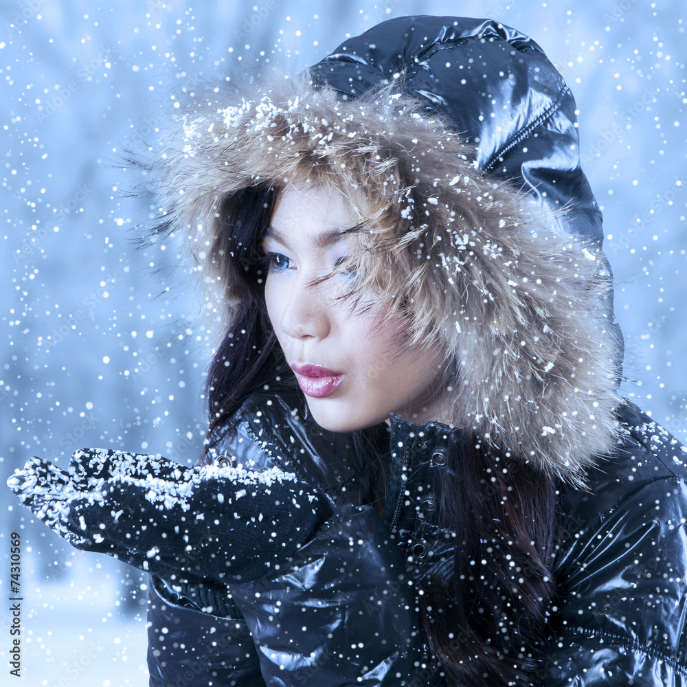 Young woman blowing snow on hands Young woman blowing snow on hands