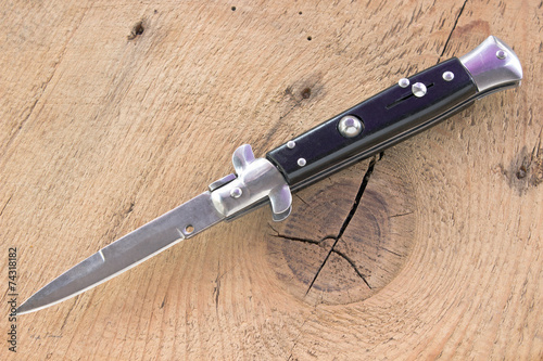 Switchblade knife on wooden background