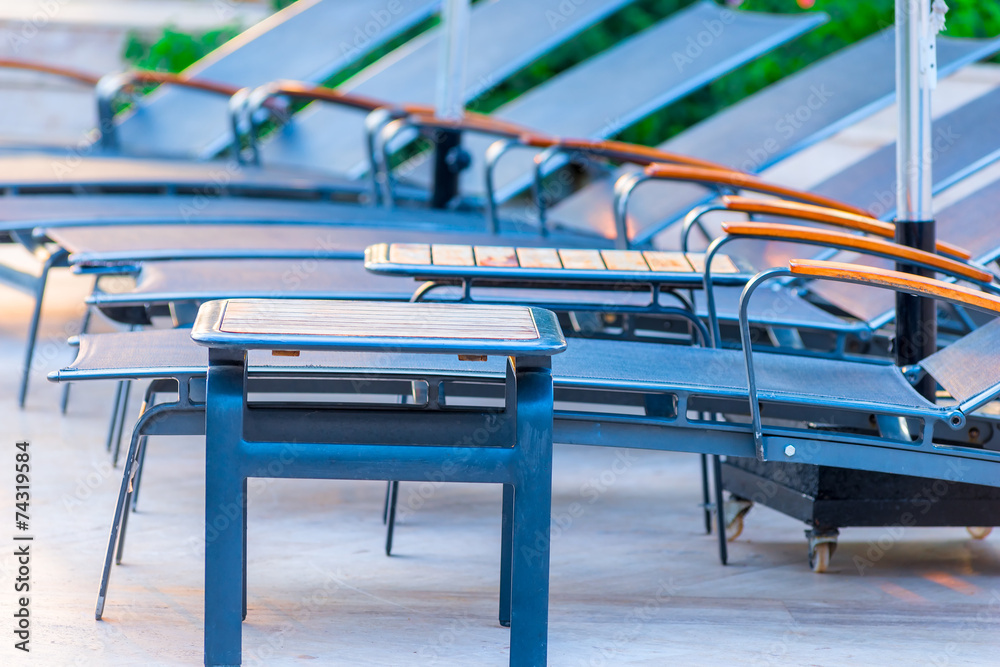 closeup shot empty chairs around the pool