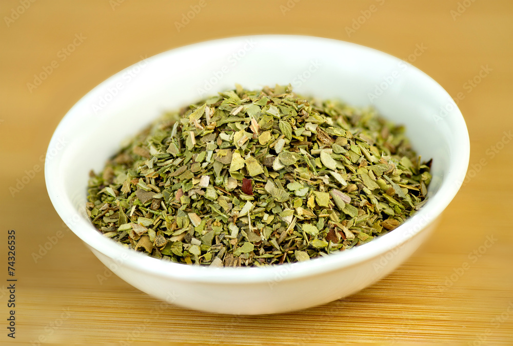 Dehydrated oregano macro in white bowl on wooden background Dehydrated oregano macro in white bowl on wooden background