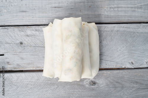Uncooked Vietnamese egg rolls on a wooden table