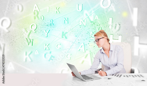 Business woman at desk with green word cloud