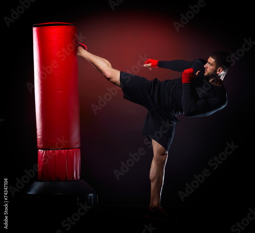 young man exercising bag boxing in studio photo