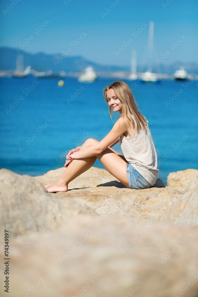 Beautiful young girl sitting on a rock
