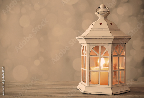 Lantern on wooden table on bright background © Africa Studio