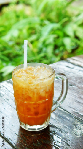 Milk tea with ice on wooden table (Thai beverage)