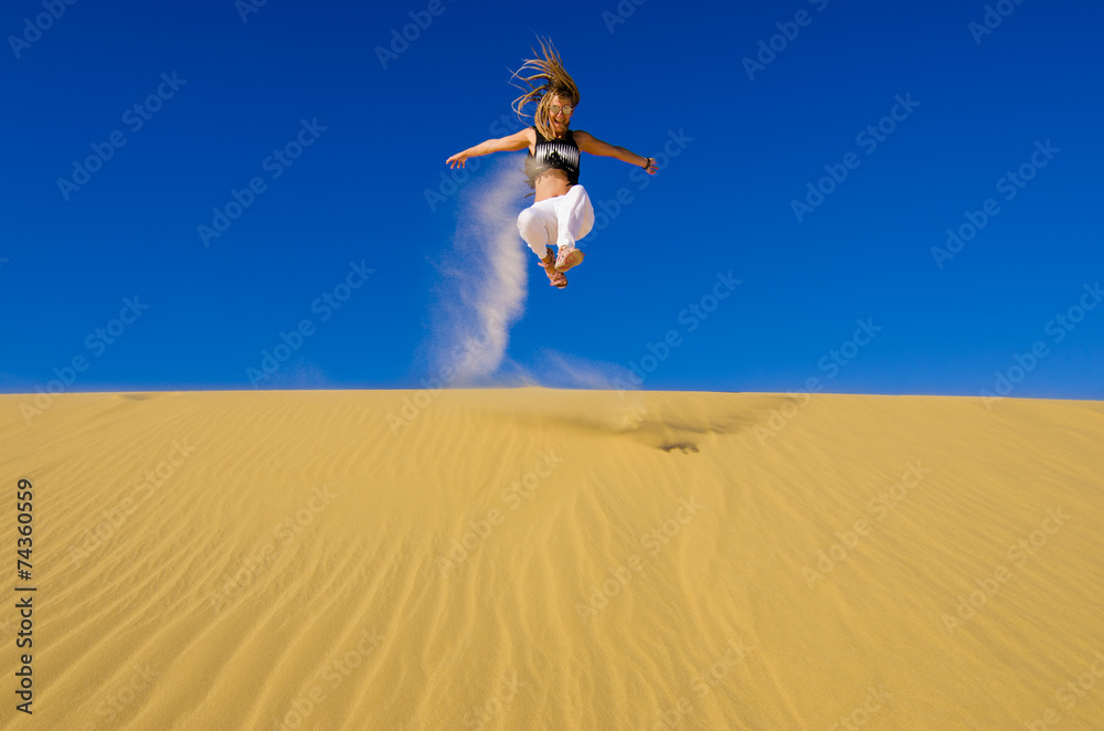 girl jumping on the yellow sand dune