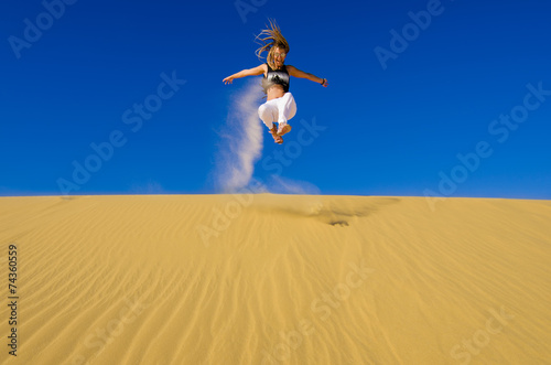 girl jumping on the yellow sand dune