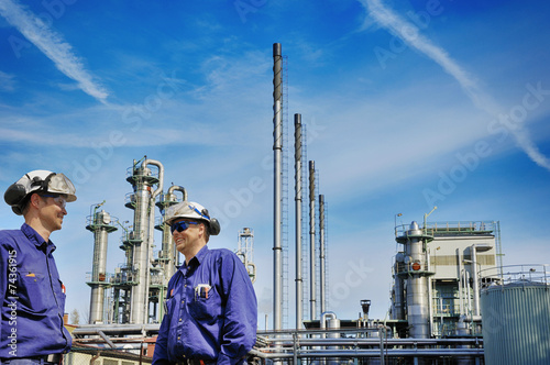 oil workers in front of large chemical refinery