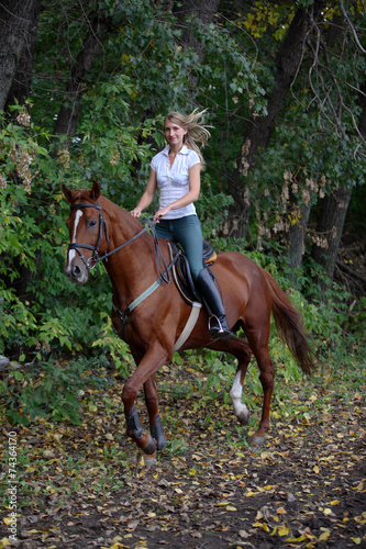Joyful girl riding horse in forest