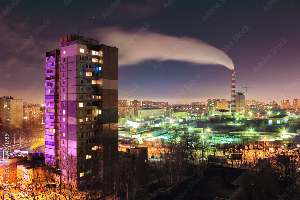 Fototapeta premium The smoke from industrial pipe in the city at night