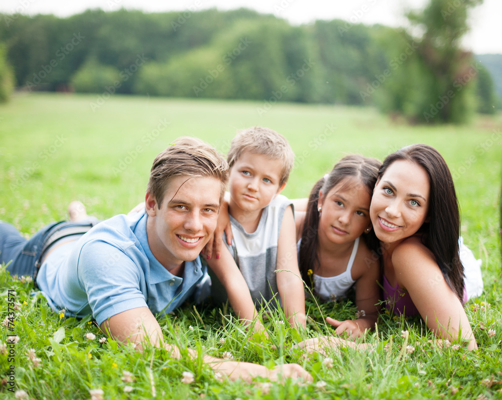 Junge glückliche Familie liegt im Sommer im Gras Junge glückliche Familie liegt im Sommer im Gras