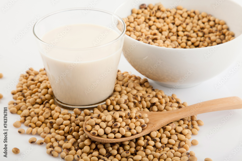 Soy milk in glass with soybeans and wooden spoon Soy milk in glass with soybeans and wooden spoon
