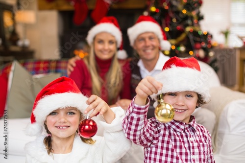 Cute little siblings wearing santa hat holding baubles