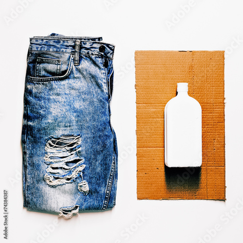 Fashion design grunge style. Vintage blue jeans and white bottle photo