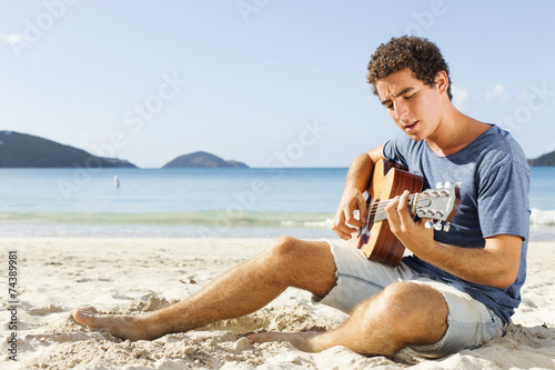 Young men playing guitar on the beach