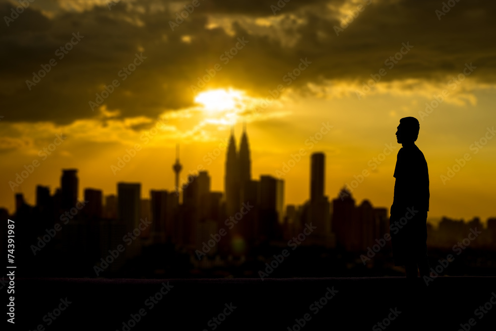 Silhouette of a man looking at the city from distance