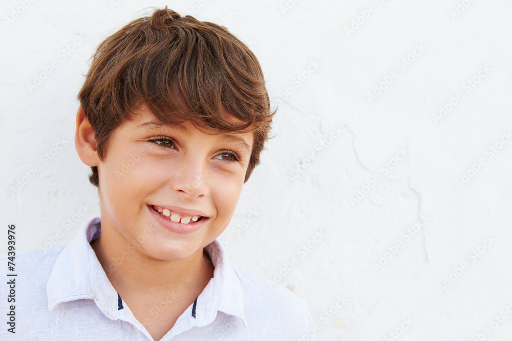 Smiling Young Boy Standing Outdoors Against White Wall Smiling Young Boy Standing Outdoors Against White Wall