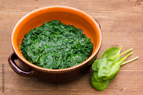 Spinach cooked in a pan on wooden table