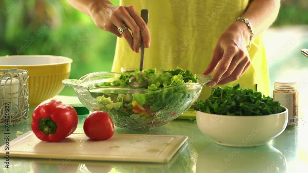Woman hands mixing salad with spoon in kitchen at home