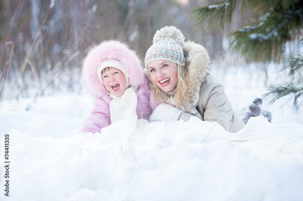 Happy mother and kid lying in snow outdoor Happy mother and kid lying in snow outdoor