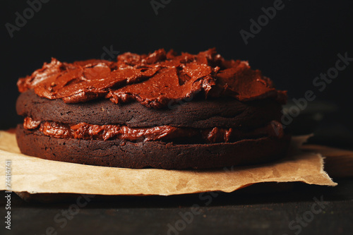 Chocolate cake with chocolate cream on wooden table close-up