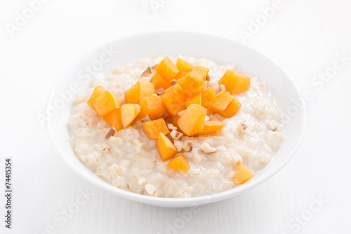 oatmeal with fresh apricots and nuts on a white wooden table