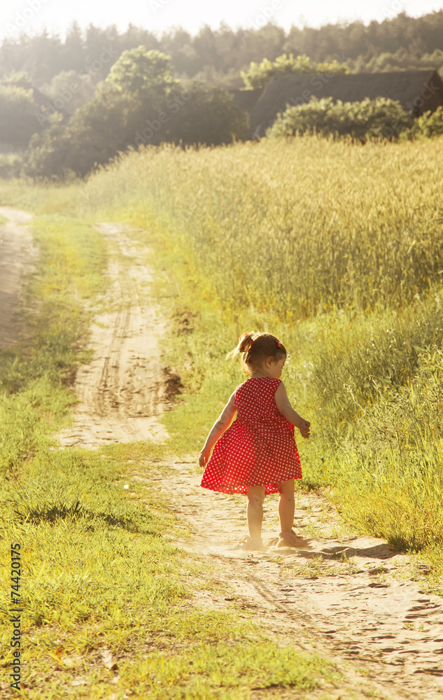 Little girl in run in a summer field. Toned