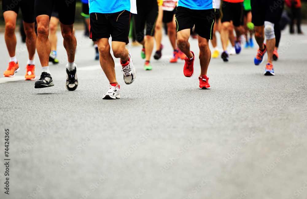 Unidentified marathon athletes legs running on city road 